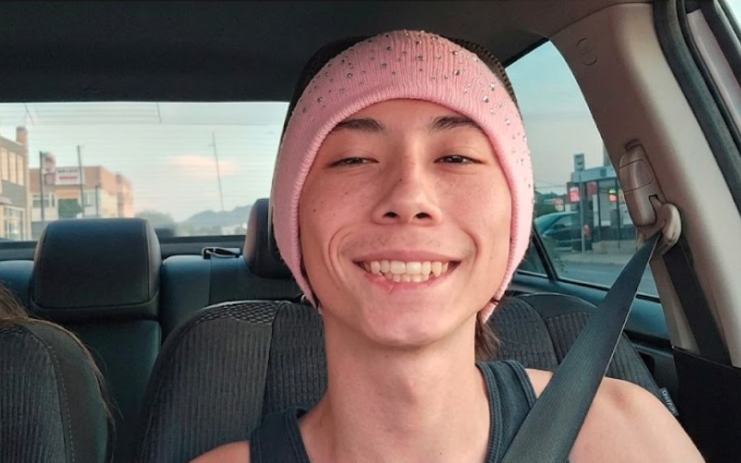 Logan grinning in a pink beanie, taking a selfie in the car